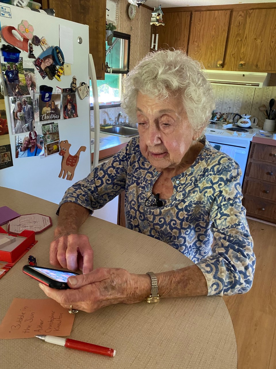 101-year-old Ruth Thompson scrolls on her iPhone while standing at kitchen counter