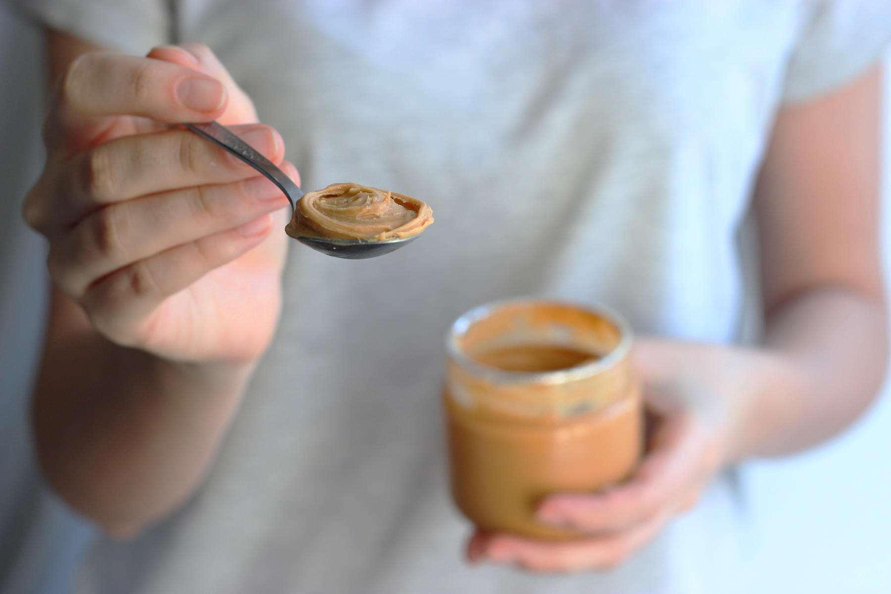 Hand Holding Spoon of Peanut Butter