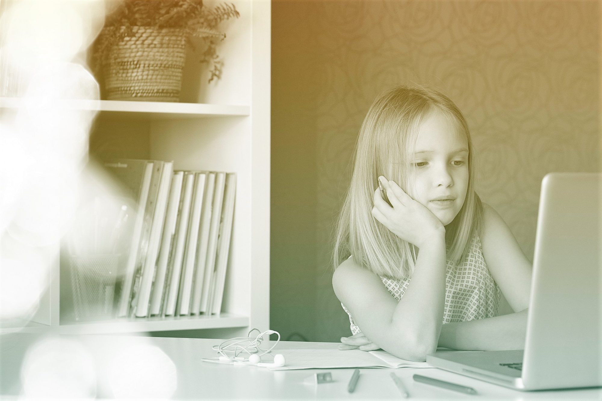 Girl sitting at table at home using laptop