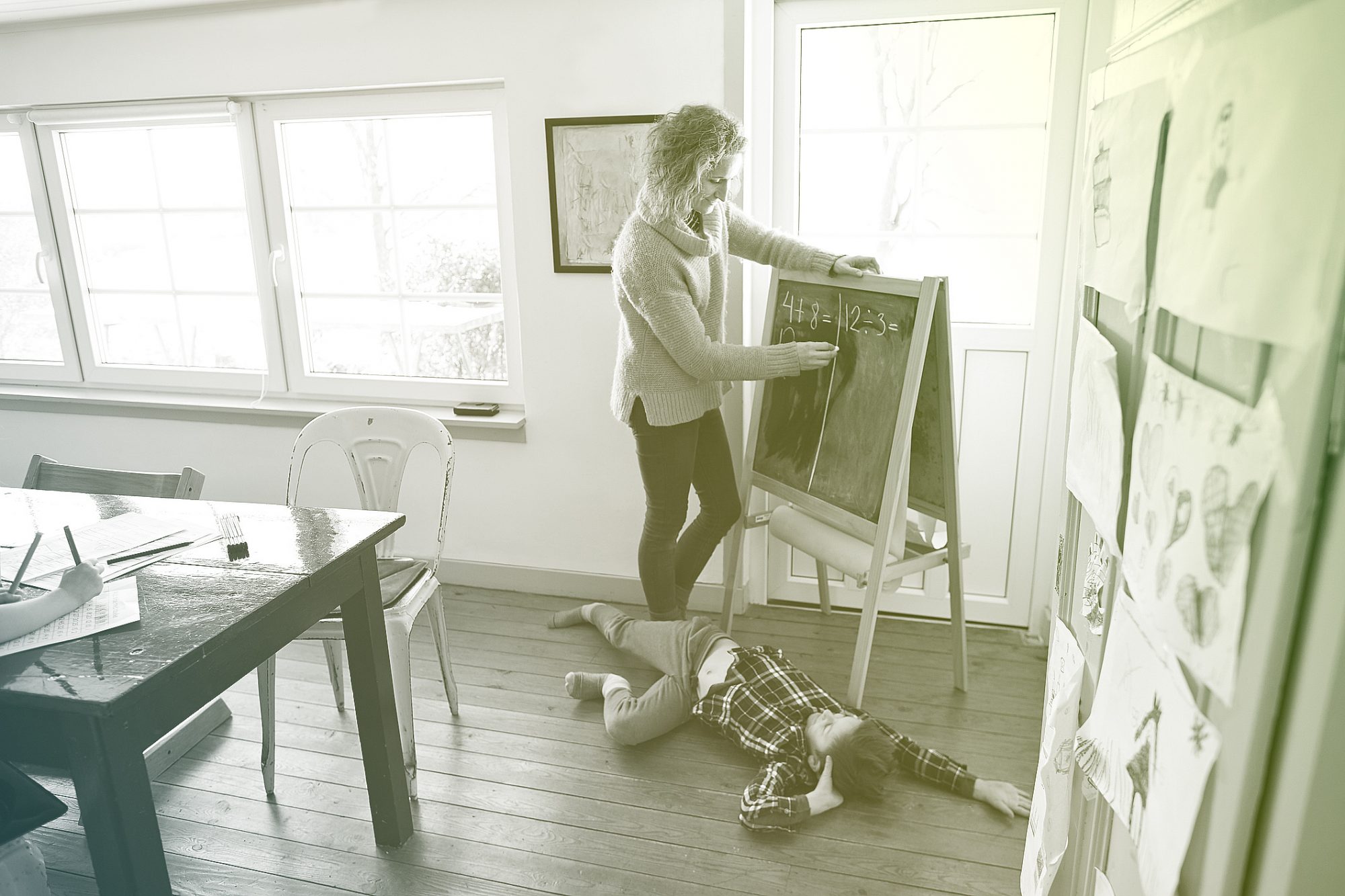 Mother using blackboard homeschooling son laying on floor