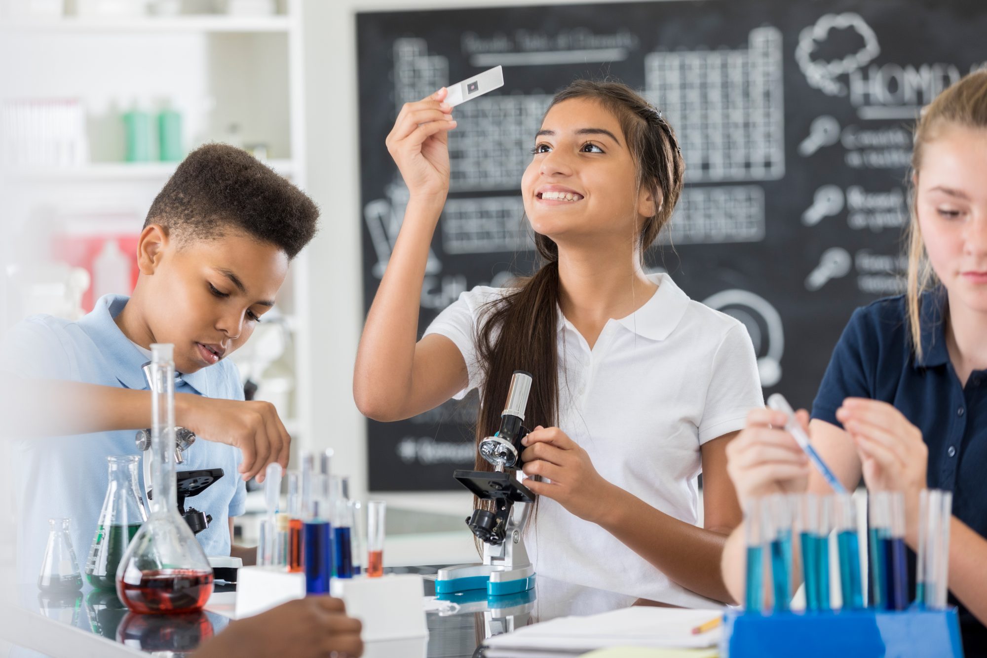 middle school student examines microscope slide