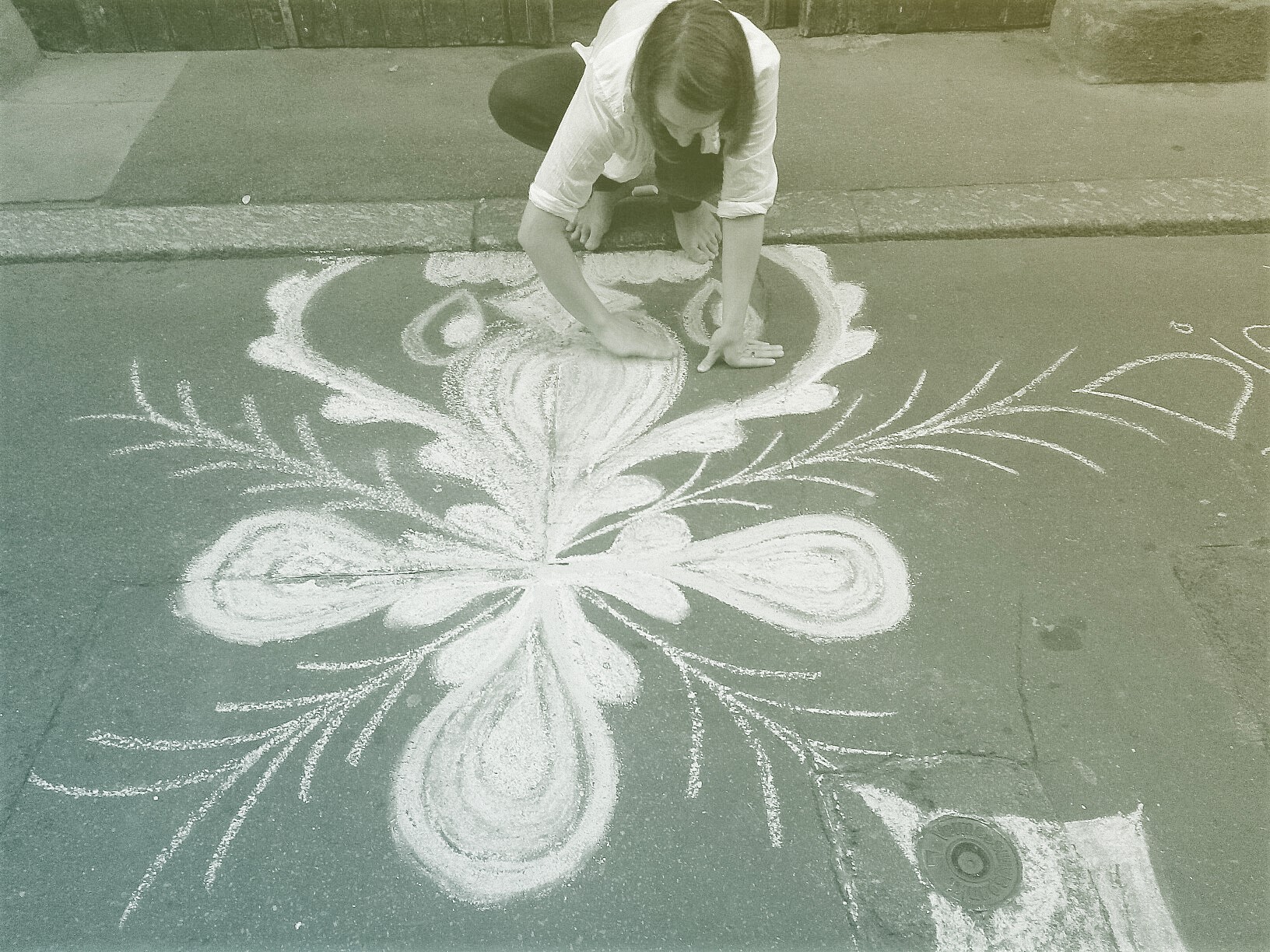 High Angle View Of Artist Drawing On Street With Chalk